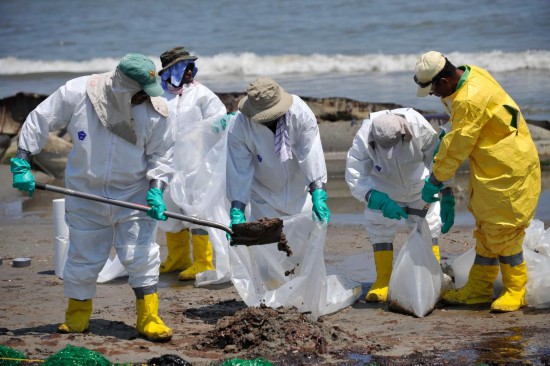 照片拍攝于2010年5月24日，在美國路易斯安那州南部的佛瓊港，清潔工人正在清理海灘上的油污。新華社記者張軍攝